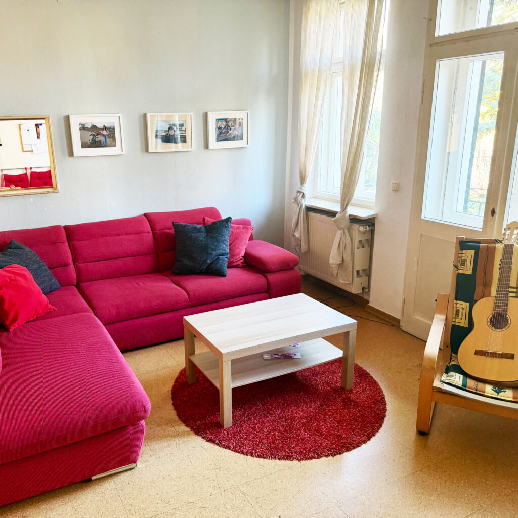 Freundlicher Wohnbereich mit Sitzecke, Tisch und Gitarre